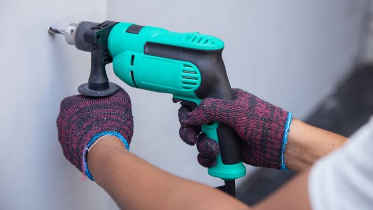 homem usando furadeira verde na parede