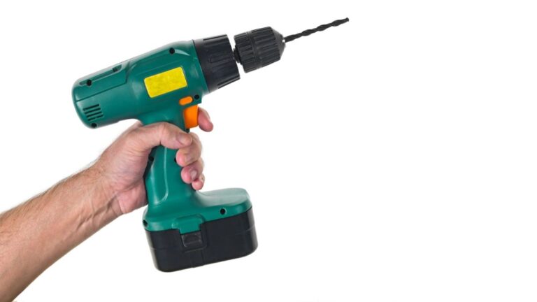 mão segurando furadeira verde