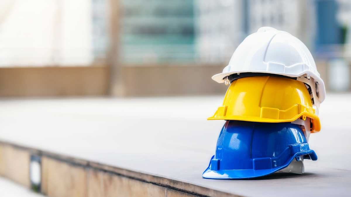capacetes de segurança amarelo, branco e azul um em cima do outro