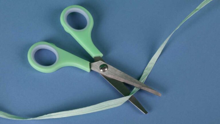 tesoura verde cortando uma fita