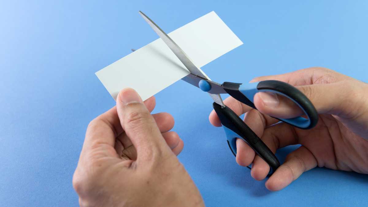 tesoura-preta-cortando-um-papel-com-fundo-azul