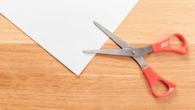 tesoura vermelha ao lado de um papel