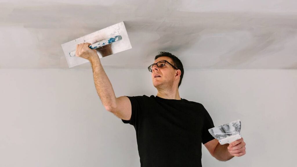 Homem usando uma desempenadeira no teto de uma construção
